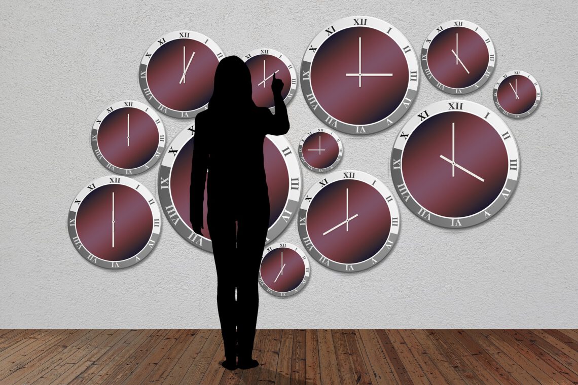 Eine weibliche Silhouette steht vor einer Wand mit Uhren. Passend zur Pomodoro-Methode